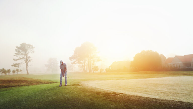 Golfer,Chipping,Onto,The,Green,At,Sunrise,On,The,Golf